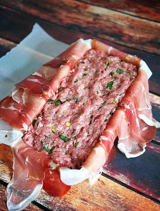 pork and veal terrine mixture placed in tin lined with prosciutto