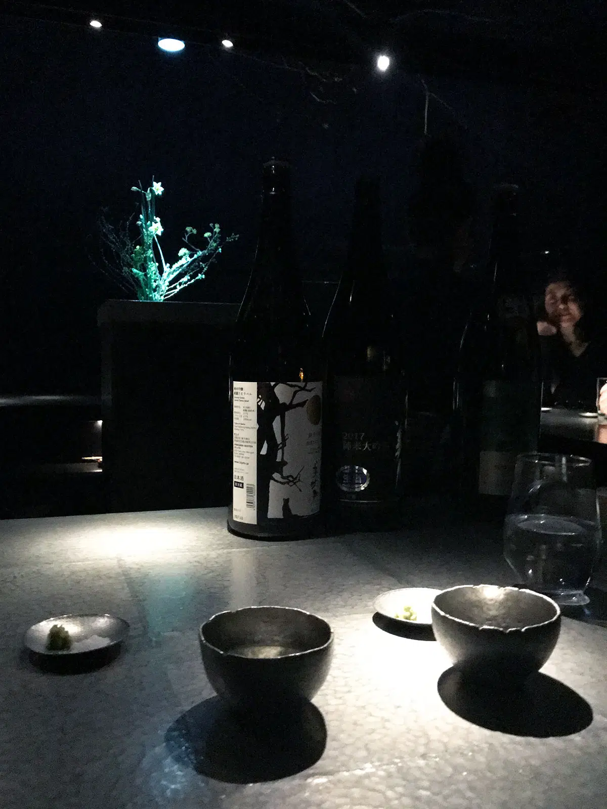 sake cups and bottle on a tin counter at Sake Bar O