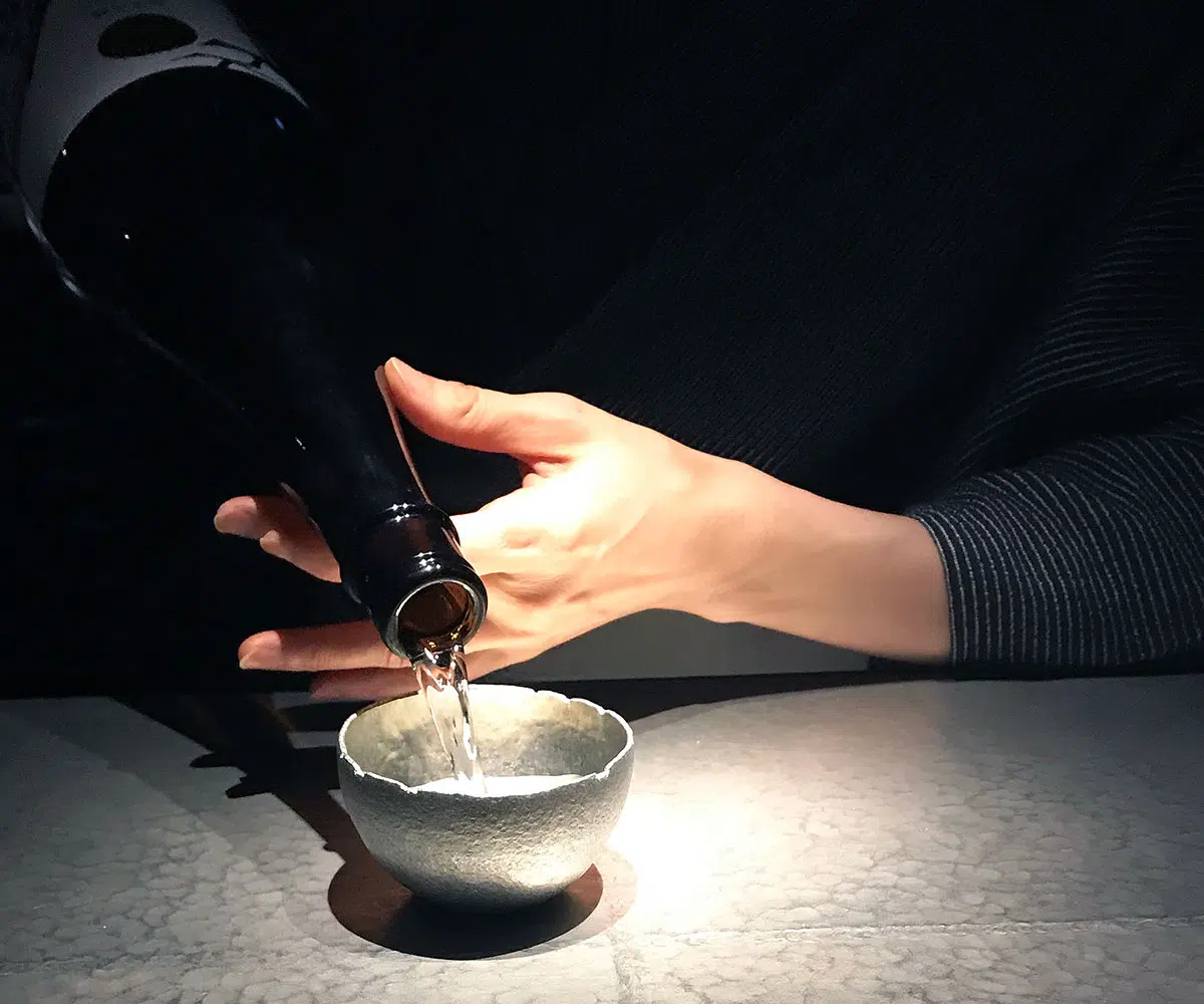 a woman pouring sake in to a sake cup