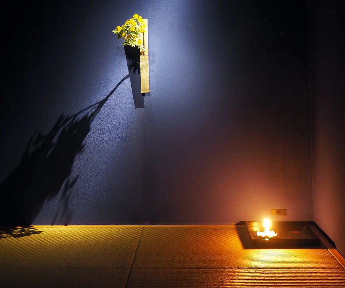 tatami mats, with candles and floral arrangement on the wall at Sake Bar O