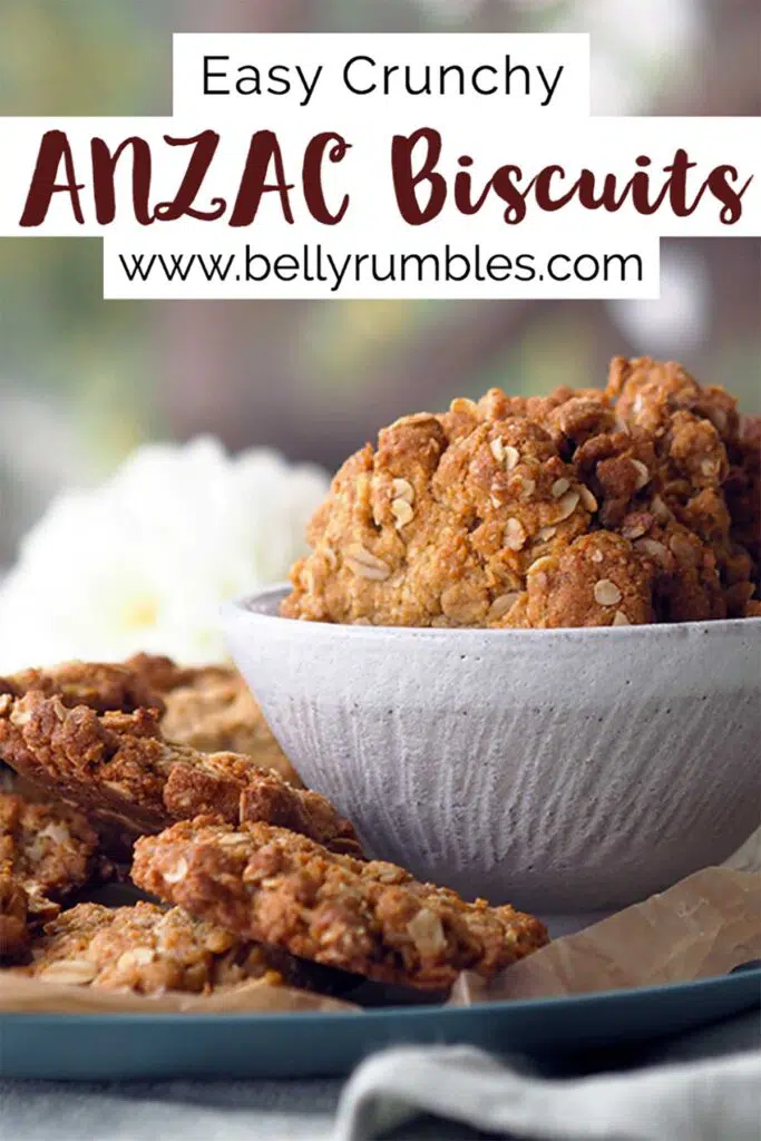 Anzac biscuits in a bowl sitting on a plate with more Anzac biscuits