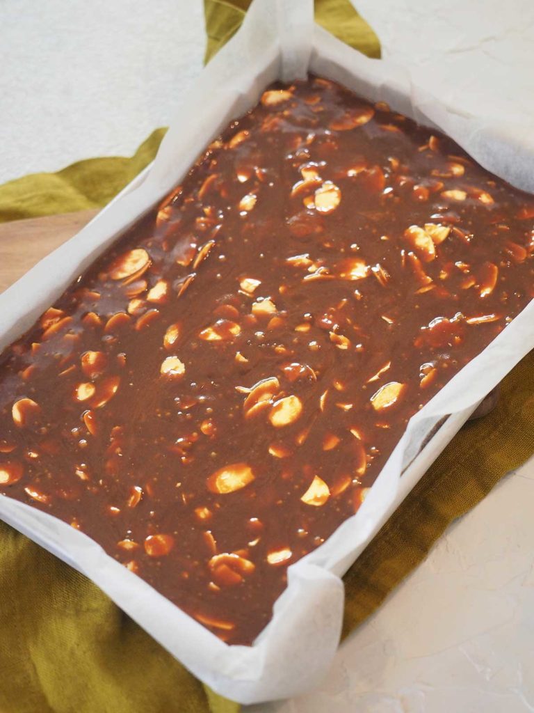 Almond toffee in lamington / brownie tin before pouring dark chocolate over the top.