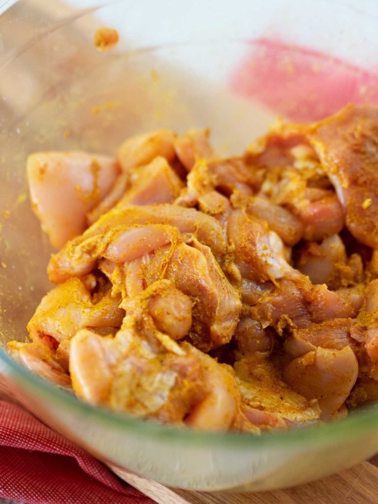 raw chicken in a bowl after being tossed in curry powder