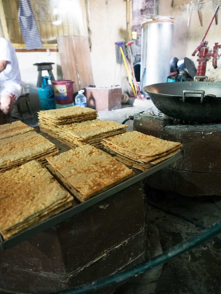 stacked sheets of baked cashew meringue on a wooden table