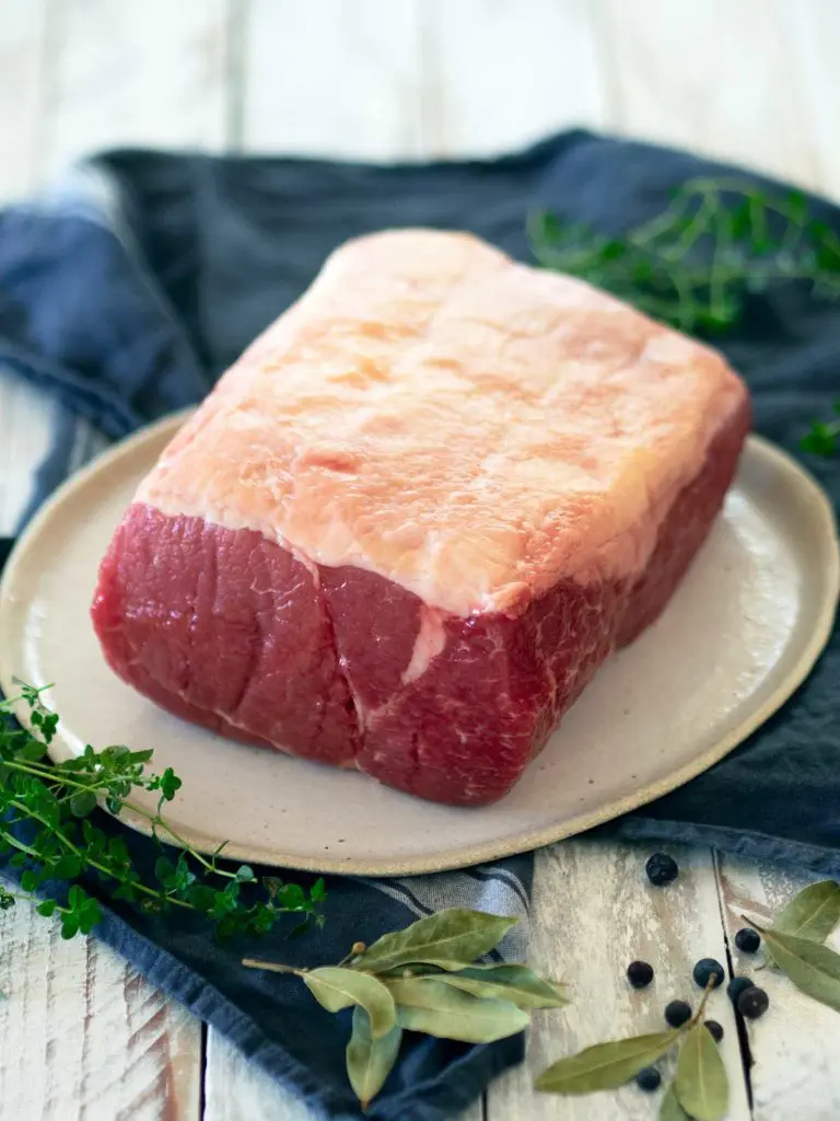 a piece of uncooked corned silverside on a plate