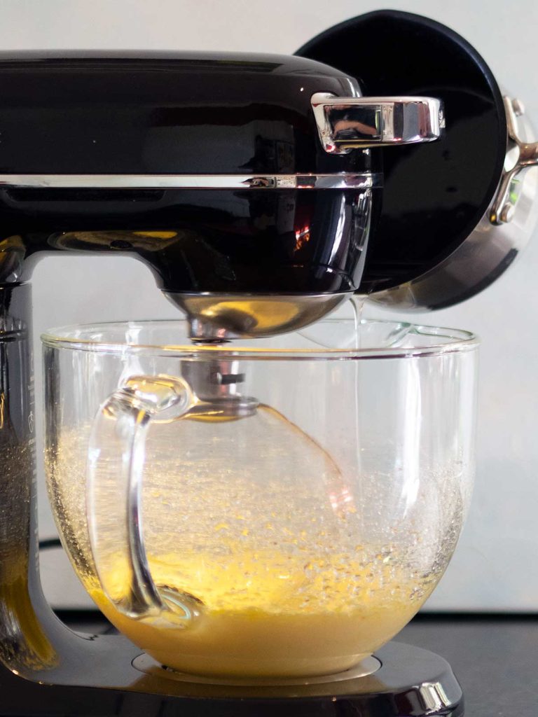 sugar syrup being poured into bowl with whipped butter
