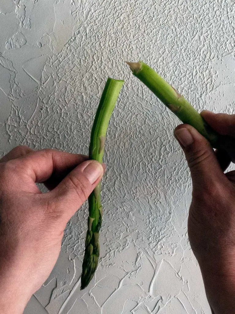 asparagus being snapped to remove the woody end