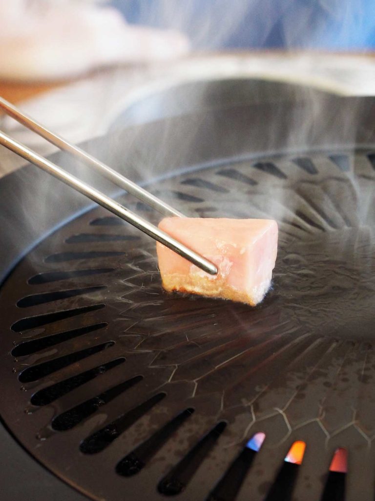 wagyu beef fat being held by chopsticks and greasing the hot grill