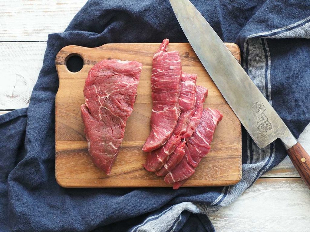 fillet steak being sliced on a wooden board