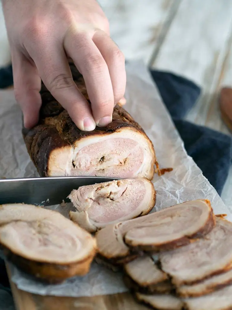 chashu pork being sliced on a cutting board