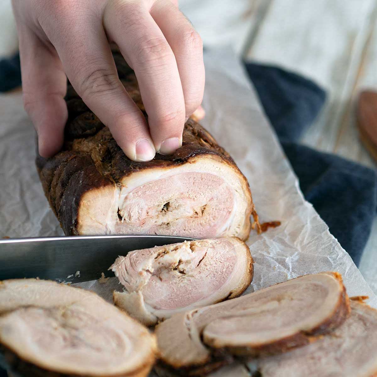 chashu pork being sliced on a cutting board