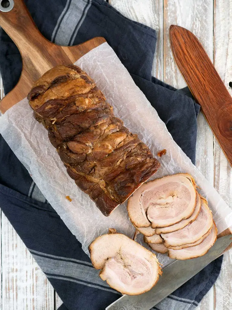 whole piece of braised pork belly with slices cut on a board