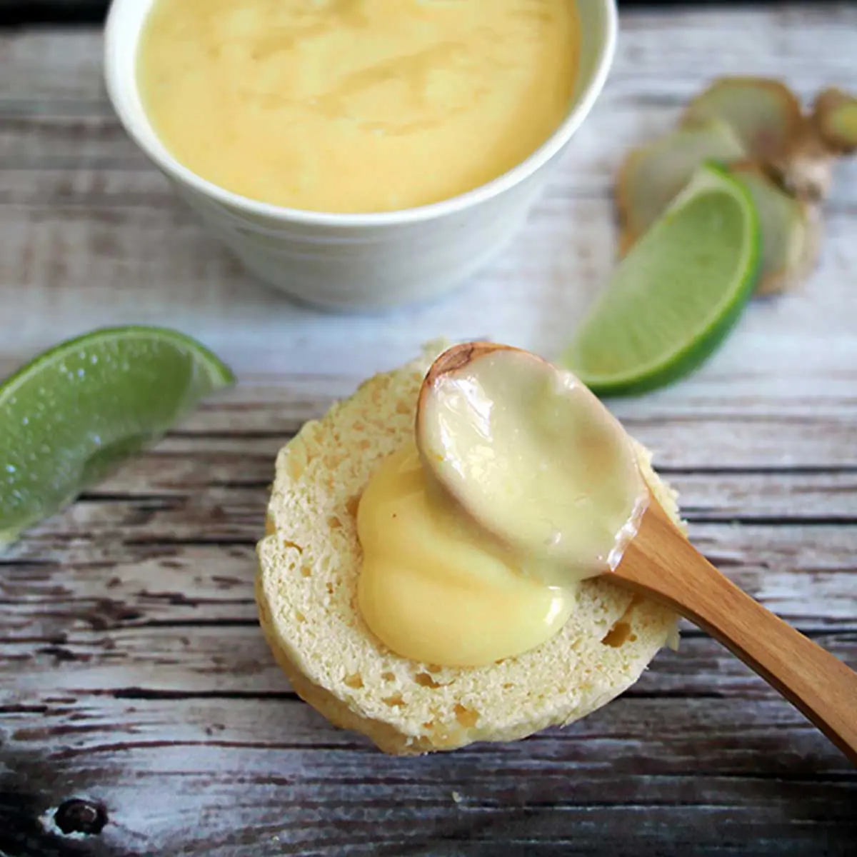 A wooden spoon placing a dollop of curd on top of a scone
