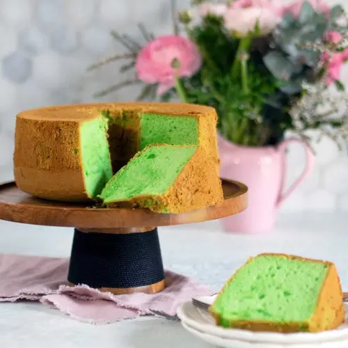 pandan cake on wooden cake stand with slices removed