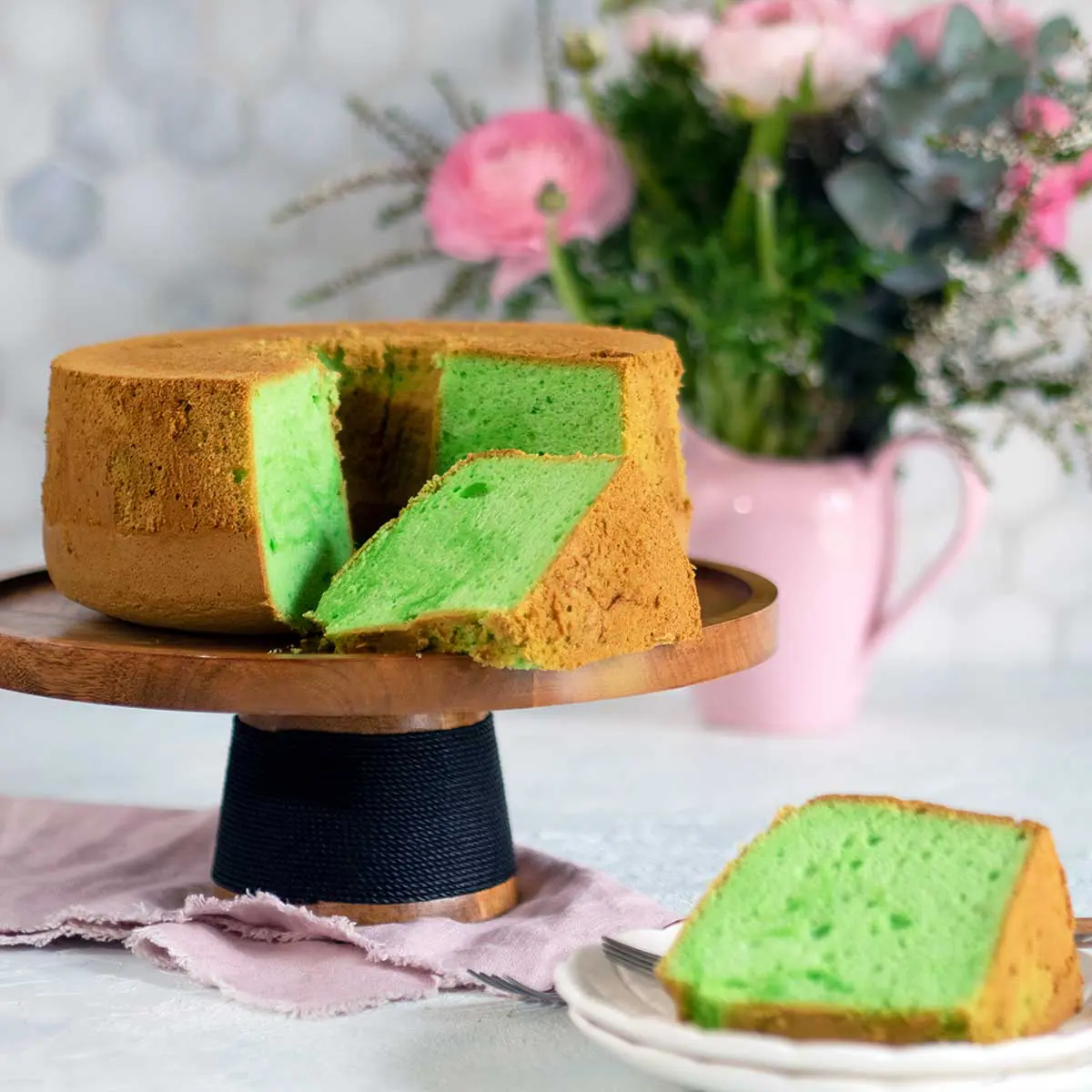 pandan cake on wooden cake stand with slices removed
