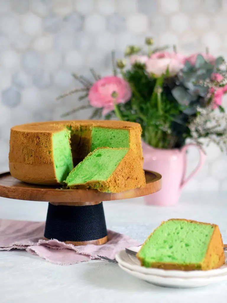 pandan cake on wooden cake stand with slices removed