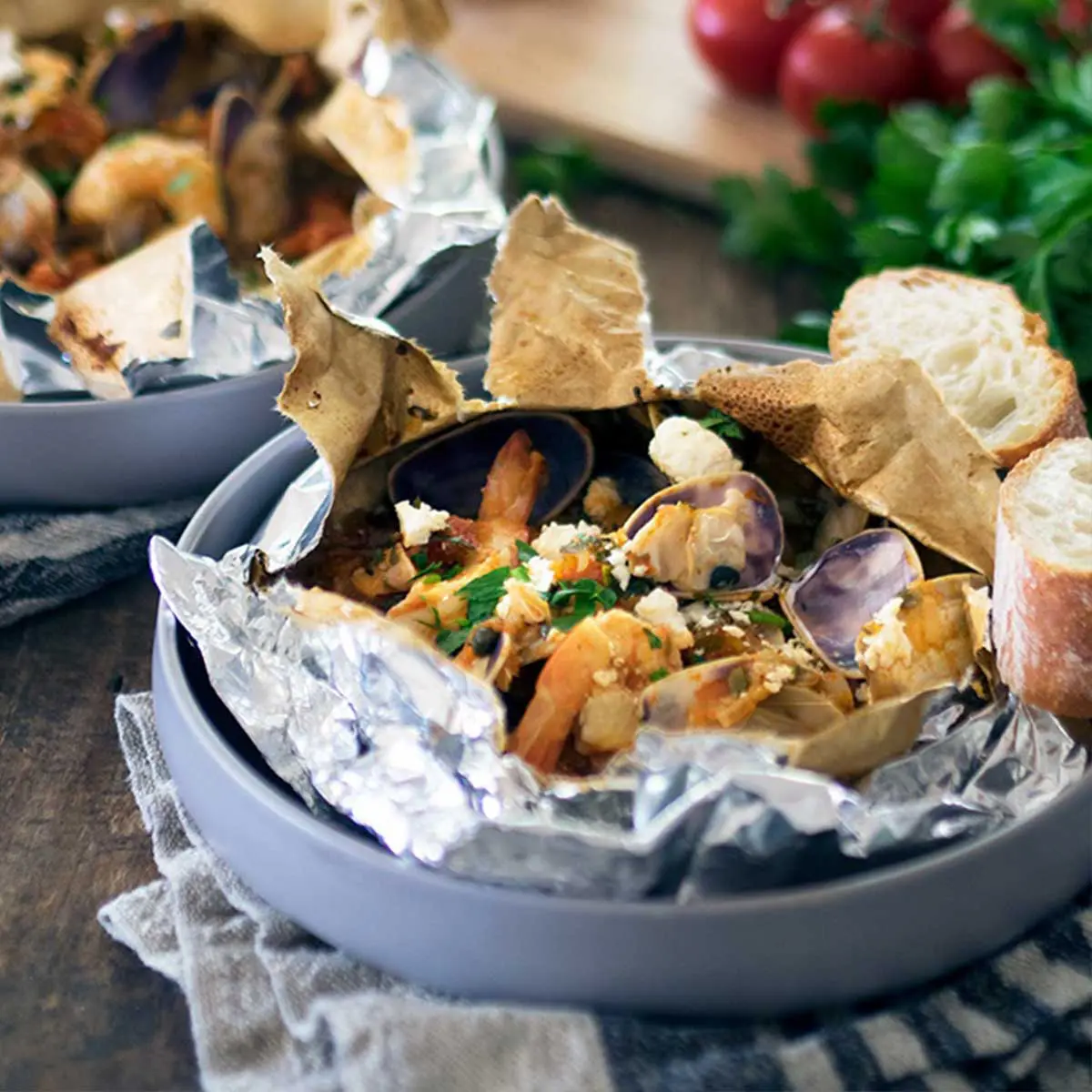 Prawns and pipis served in parchment parcels on grey-blue plates