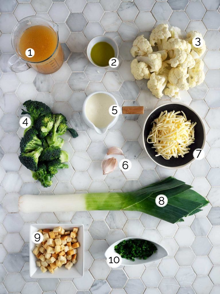 Broccoli and cauliflower soup ingredients laid out on tiles.