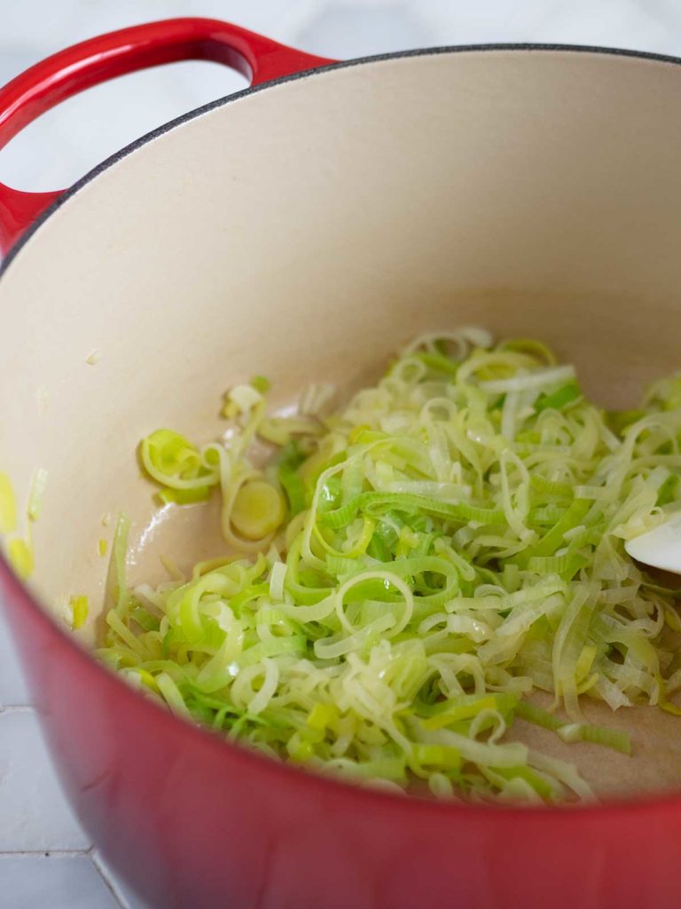 Leeks being sautéed in a pot.