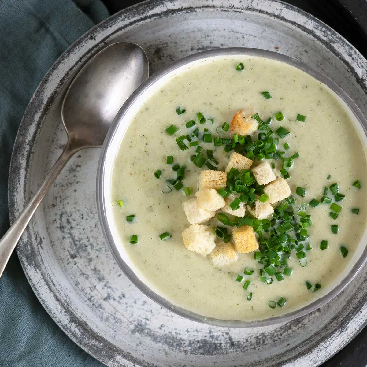 broccoli and cauliflower soup in a bowl topped with croutons and chives