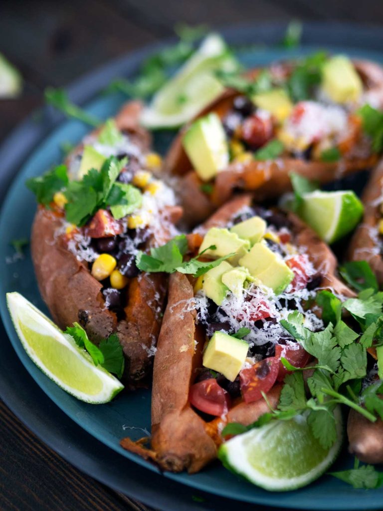 baked sweet potatoes stuffed with various ingredients on a plate