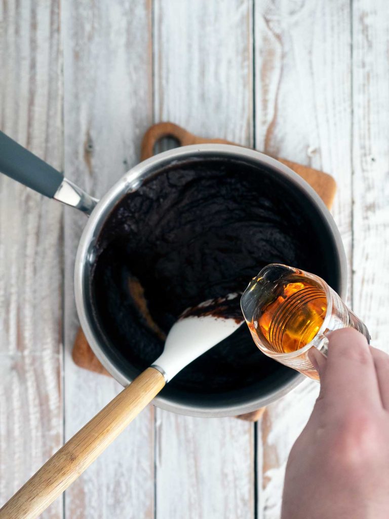 adding hennessy to the melted chocolate and cream mixture in a pot