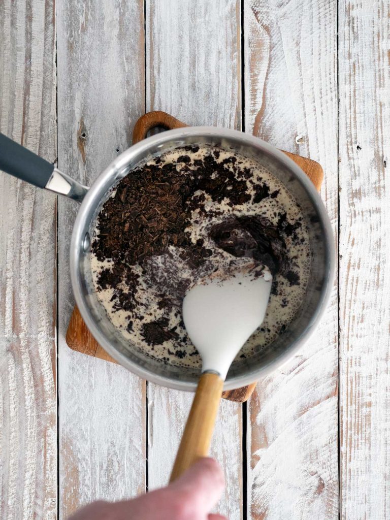 mixing grated chocolate into warm cream in a pot until melted