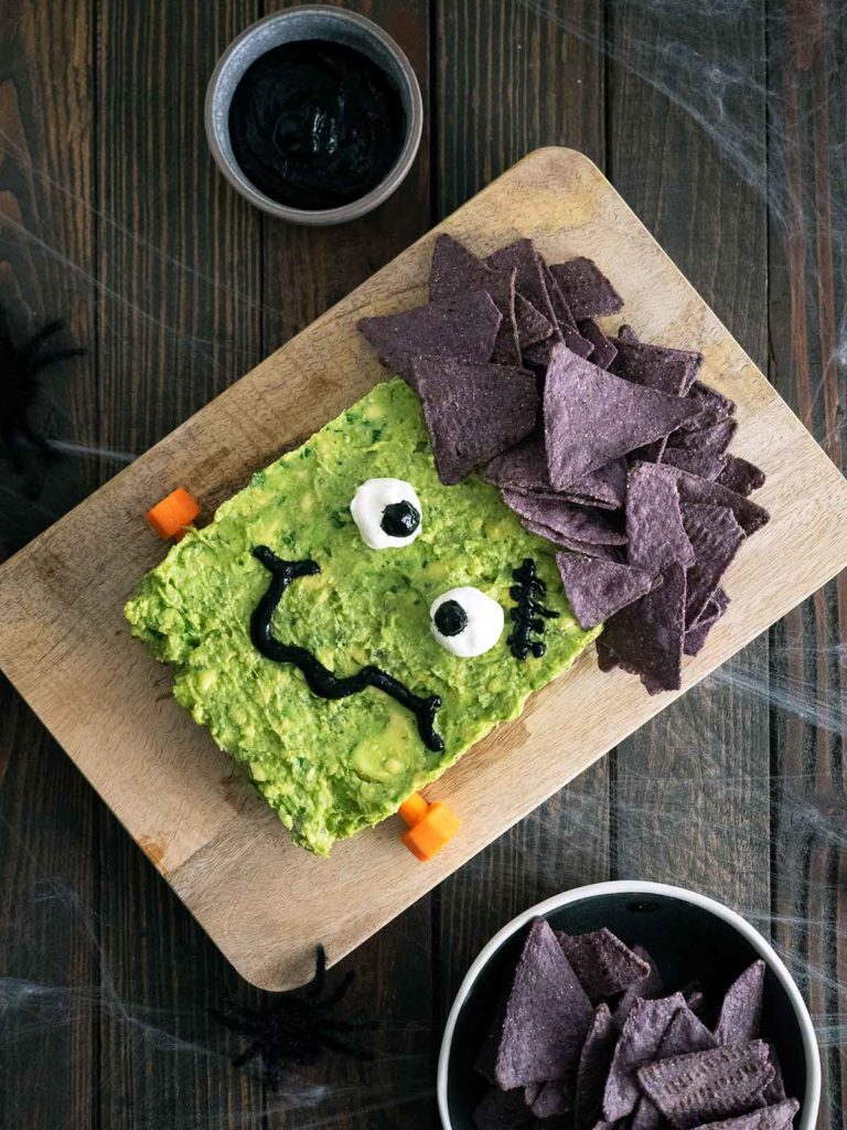 guacamole decorated to look like frankenstein on a wooden board