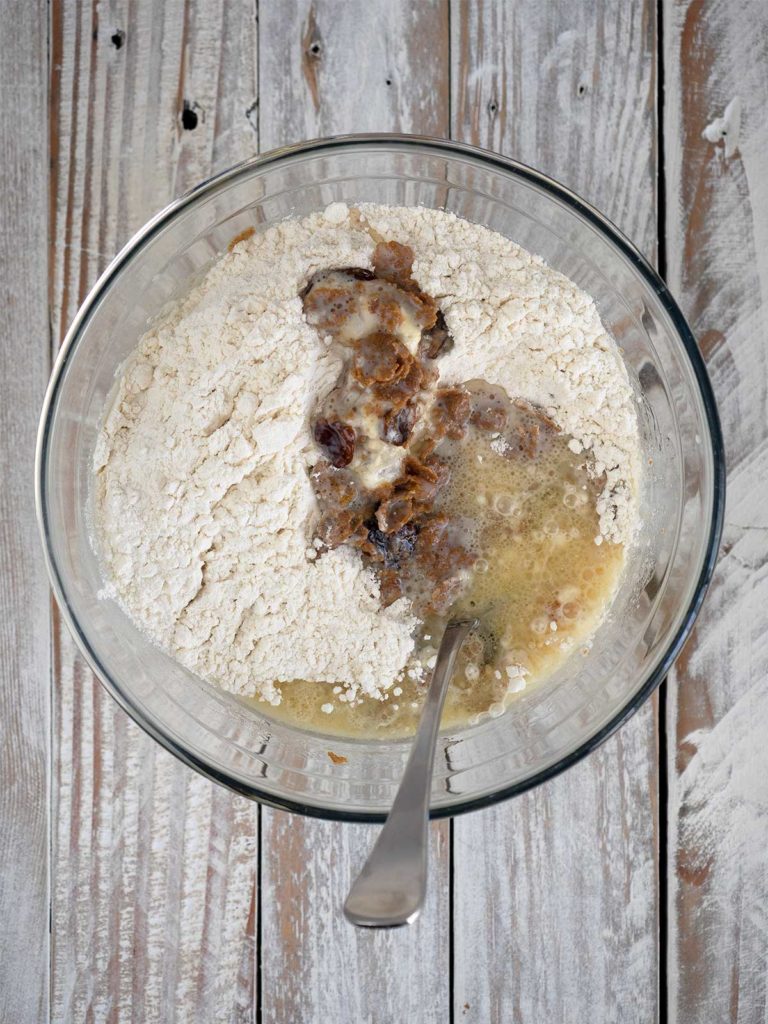 flour added on top of the bran milk mixture in a bowl with a spoon