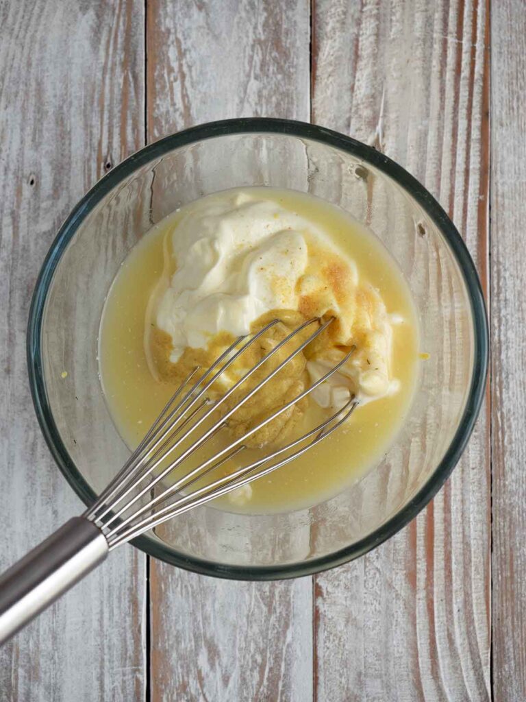 process image of dressing being whisked in a glass bowl