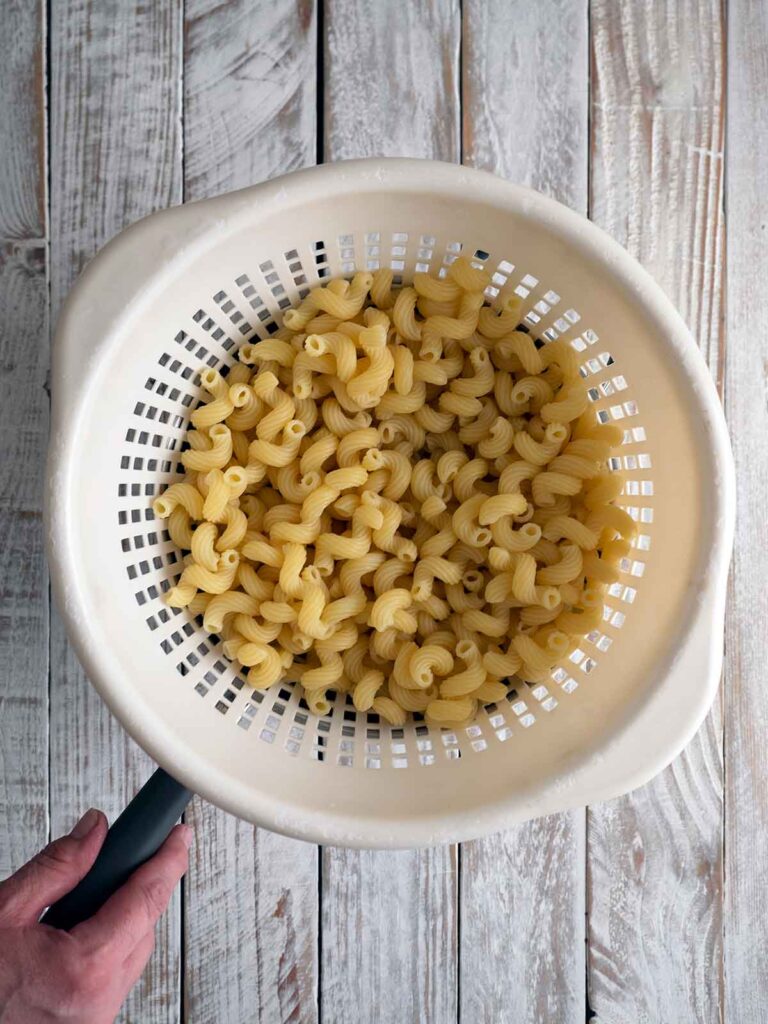 process image of pasta draining in a colander after cooking