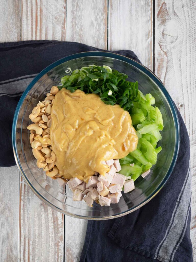 adding dressing to the ingredients in a glass bowl