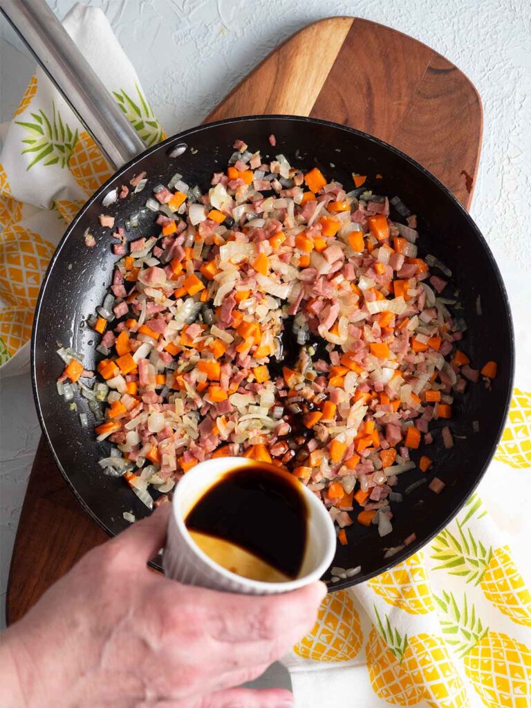 adding sauce to the ingredients in the fry pan
