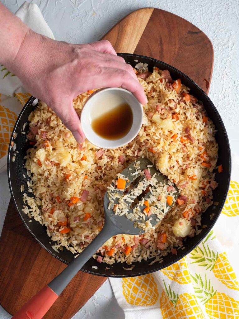adding sesame oil to the ingredients in the fry pan