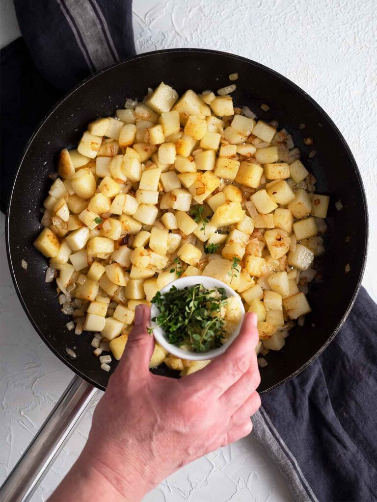 a person adding thyme to the recipe
