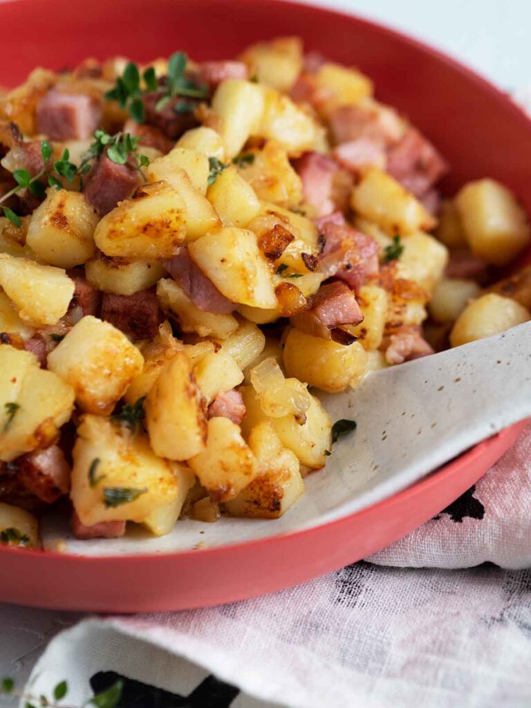 ham hash in a red bowl with serving spoon