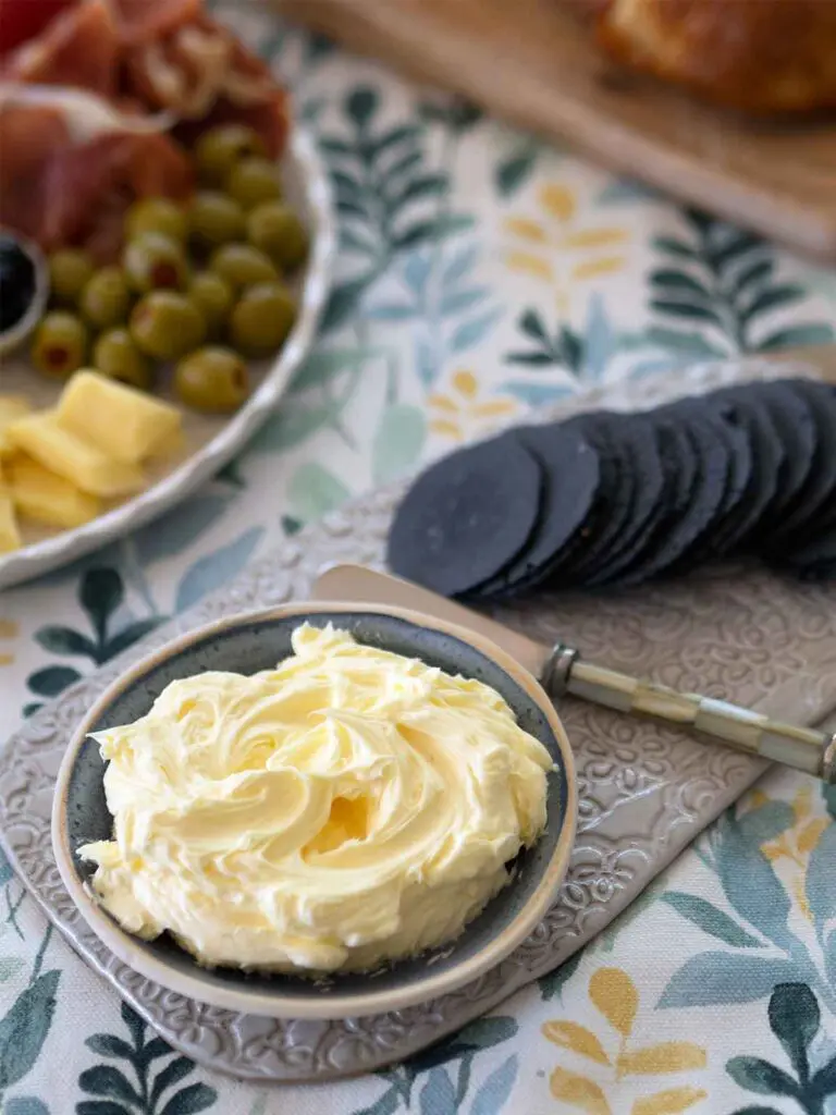 butter on table in a small dish with crackers and antipasto