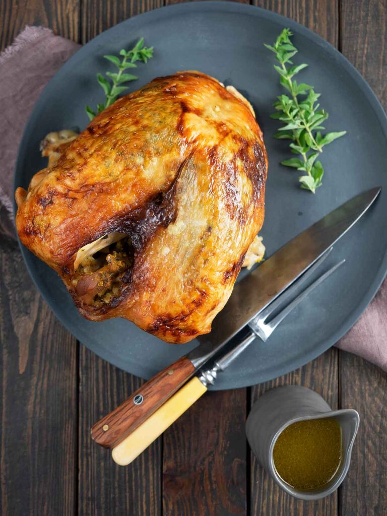 whole smoked turkey on a plate above image with carving tools