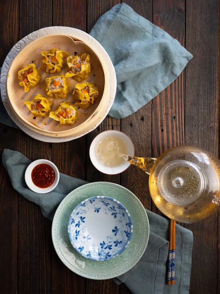 table setting with siu mai in basket and tea being poured