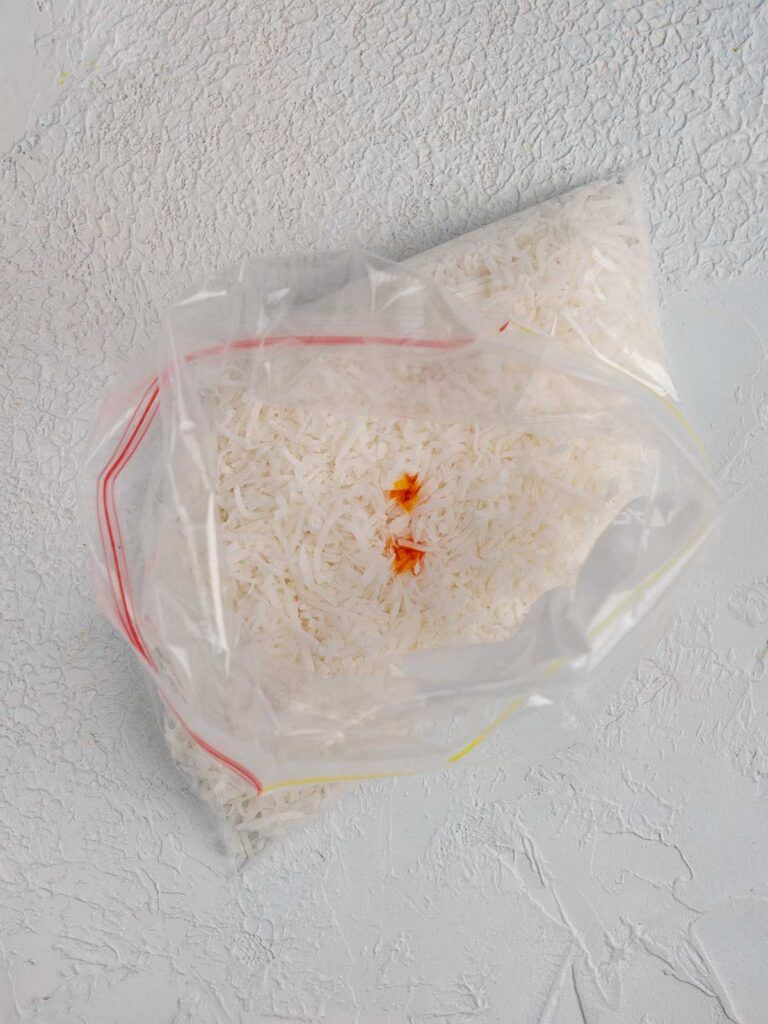 shredded coconut in a bag with drops of yellow food colouring