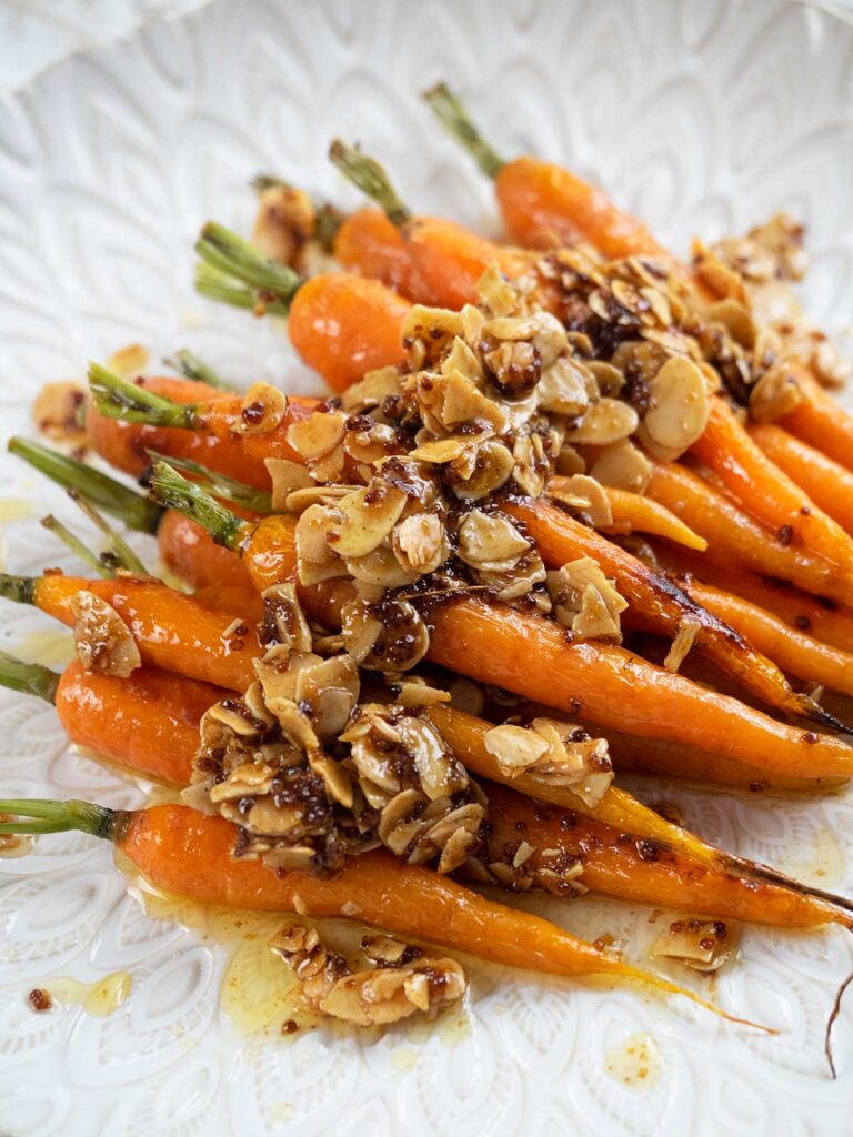 roasted dutch carrots with almonds on a white platter