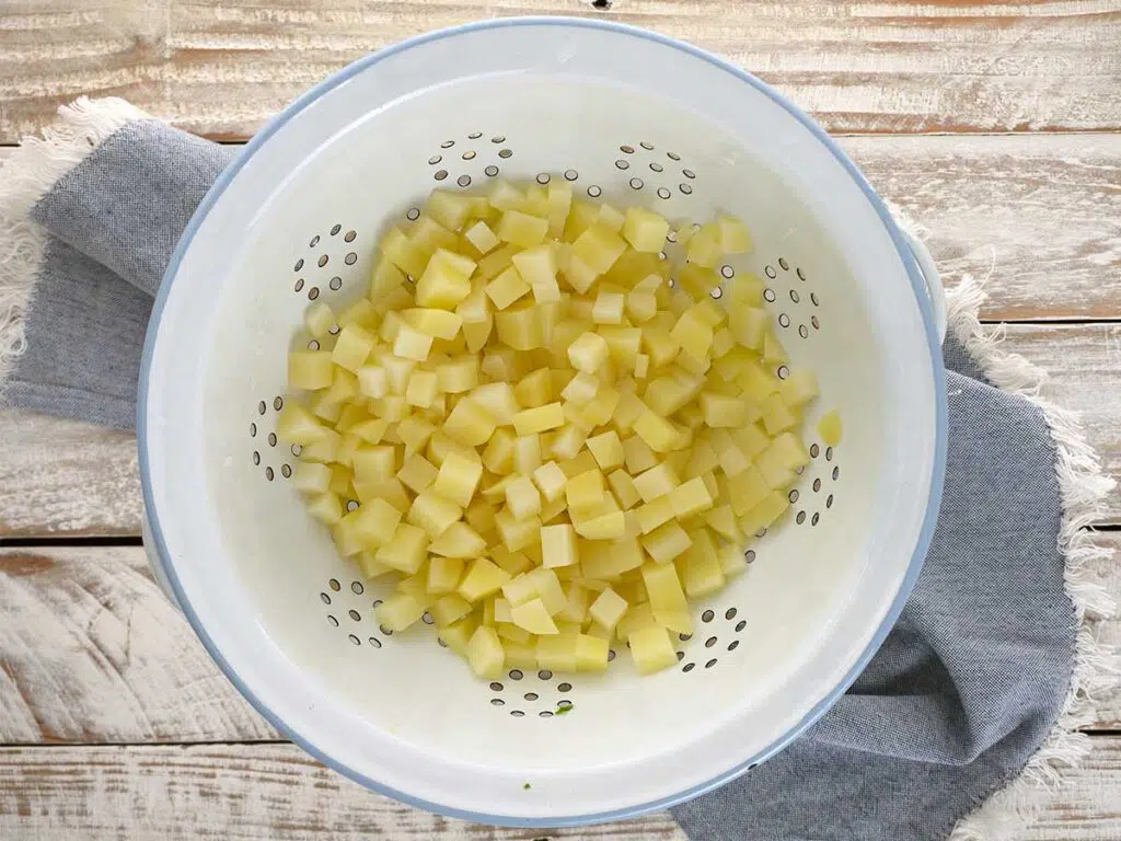 cooked diced potato in a white colander