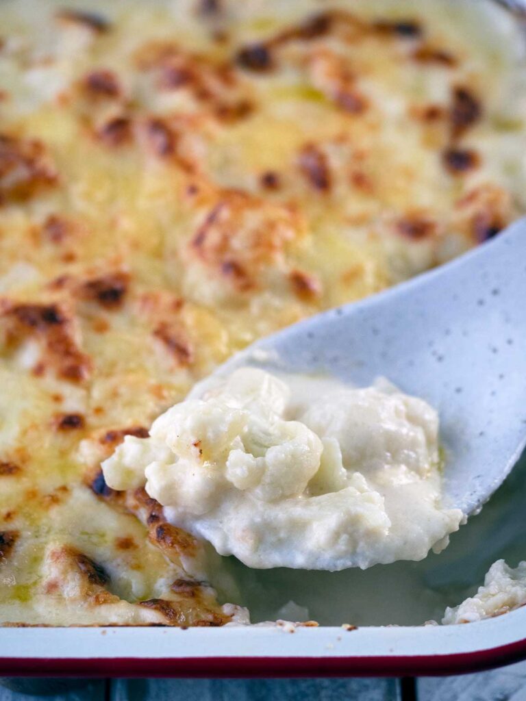 close up image of cheesy cauliflower on a serving spoon