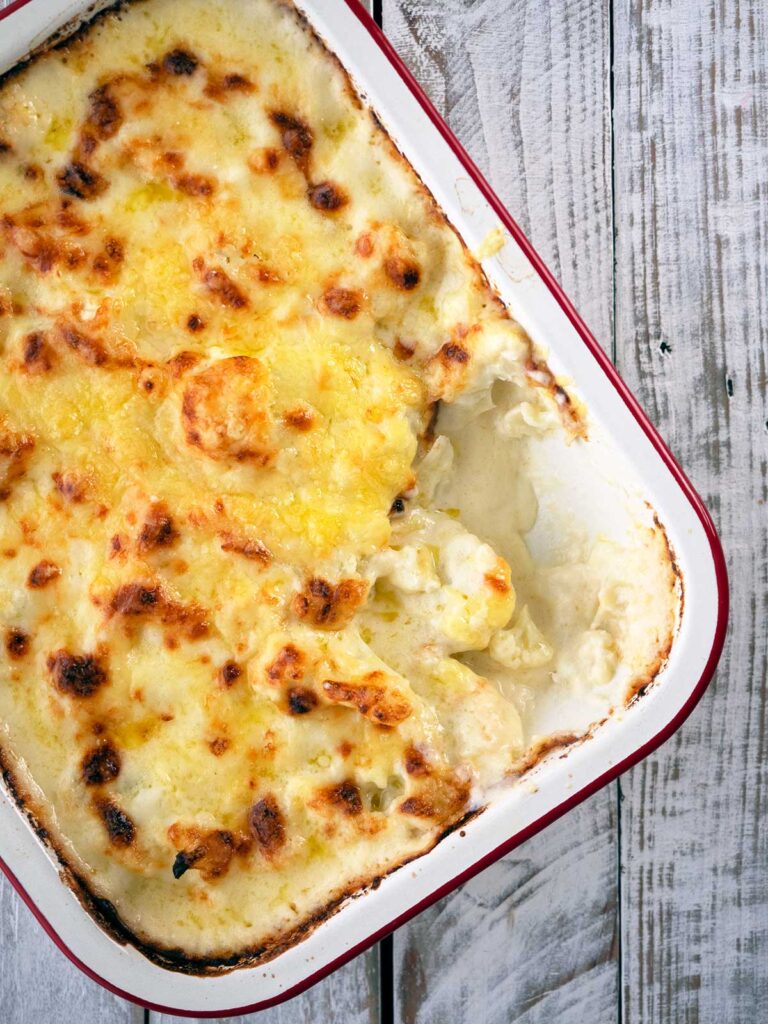 baked cheesy cauliflower in a pan with a spoonful missing