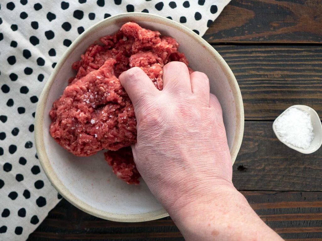 working ground beef by hand in a bowl