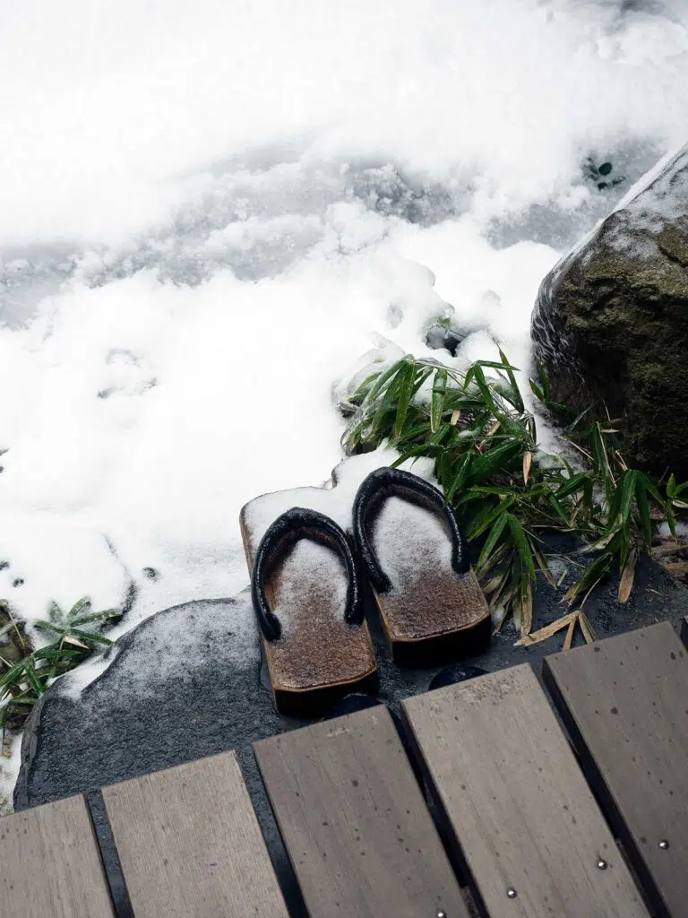 a pair of geta (japanese traditional wooden shoes) in the garden covered in snow