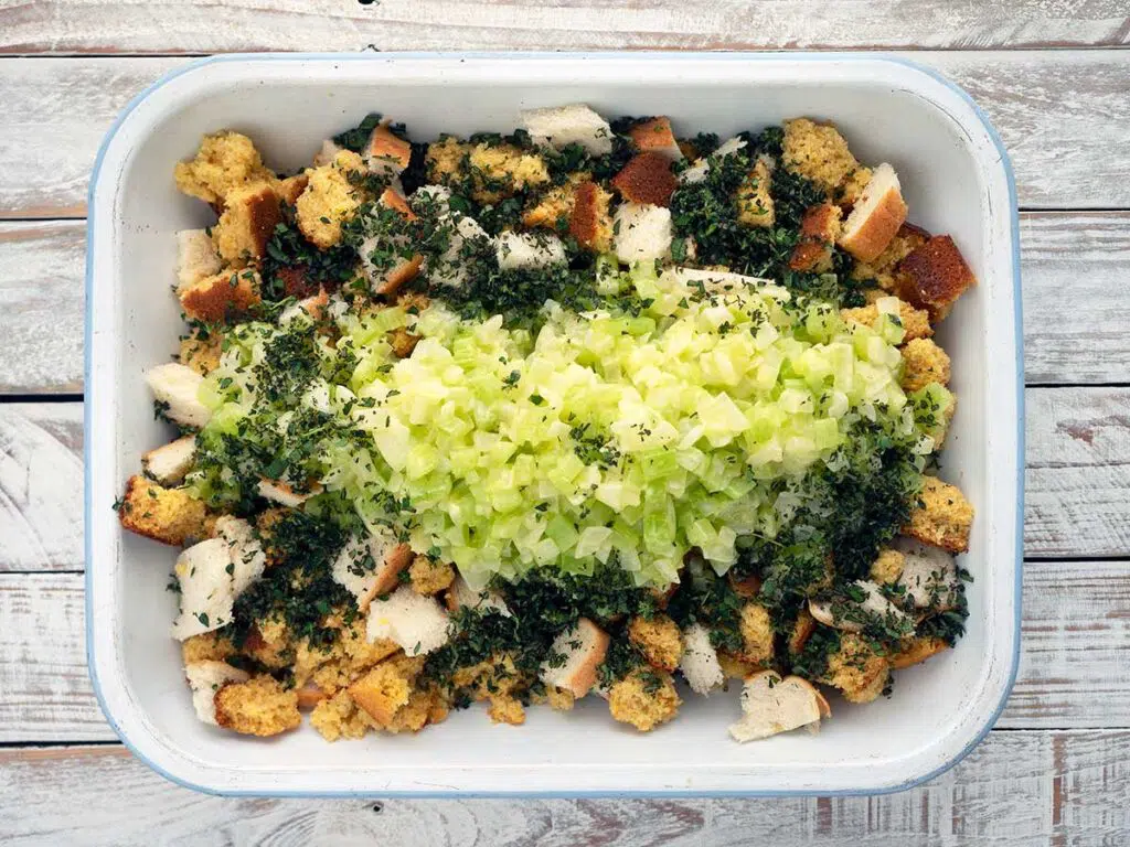 torn bread with vegetables and herbs in a baking dish