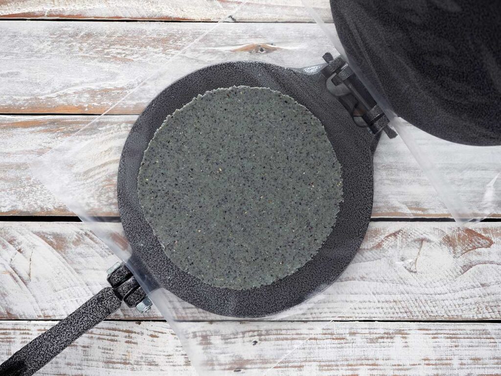 flattened tortilla on the press