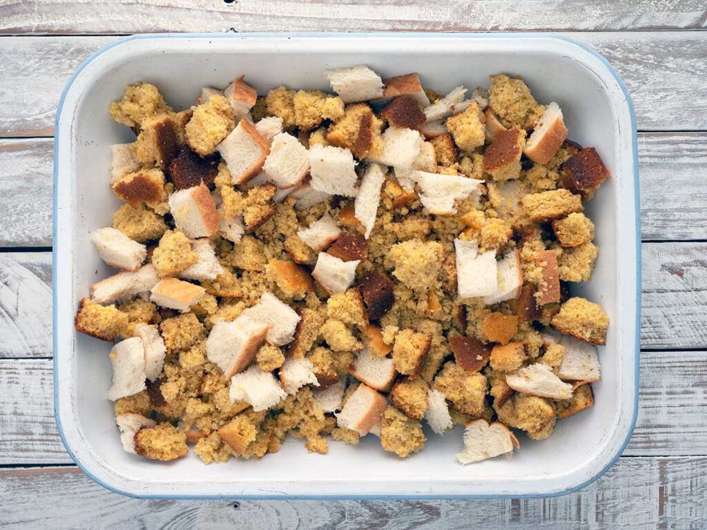 torn cornbread and white bread in a baking dish