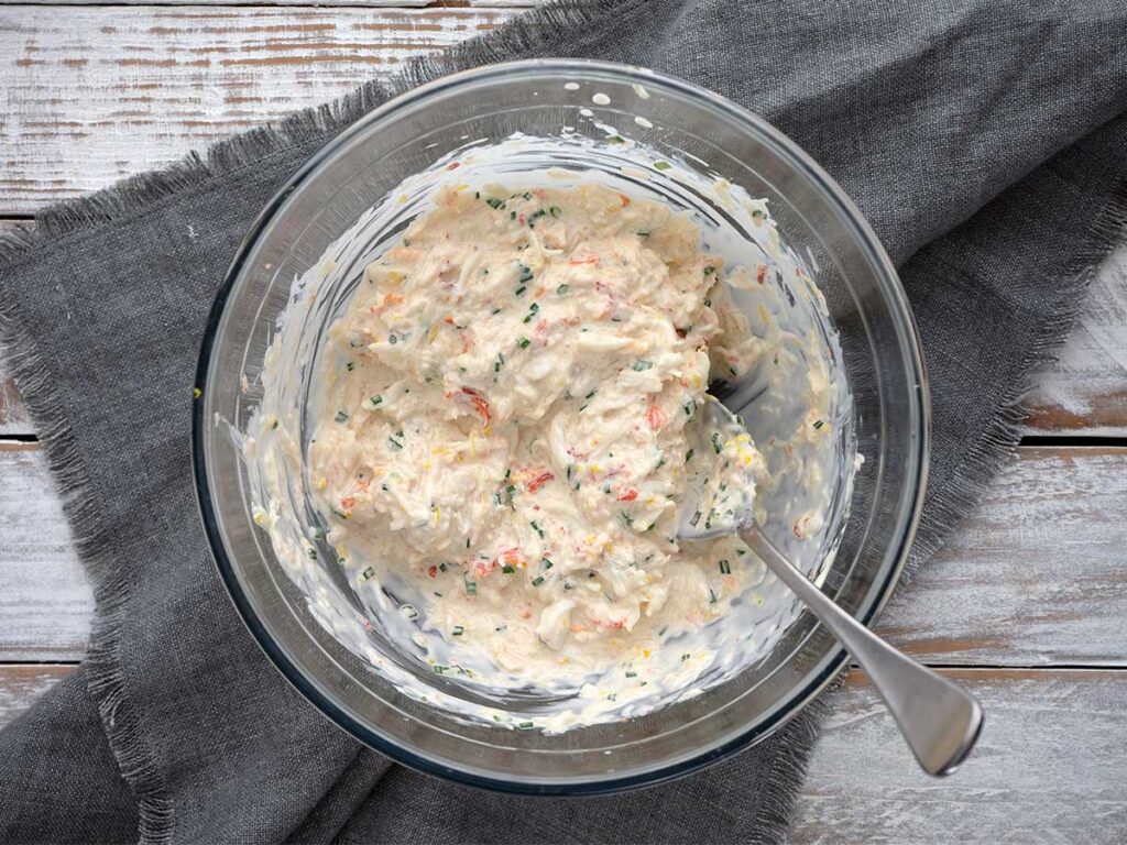 creamy crab salad ingredients mixed together in a glass bowl